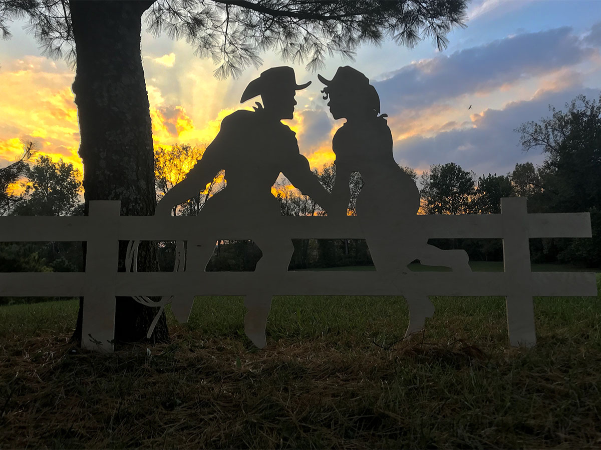 Cowboy and cowgirl sitting on a fence cut-out